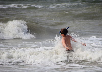 Rear view of man surfing in sea