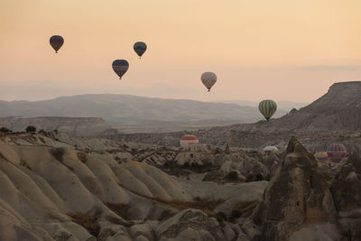 Hot air balloons on landscape against sky during sunset