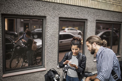 Man looking at woman using mobile phone in city