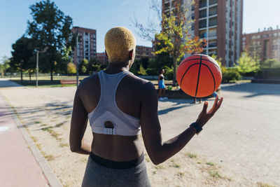 Young sportswoman playing with basketball on sunny day