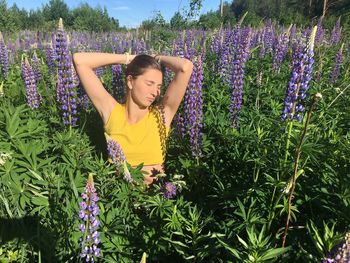 Young woman standing by purple flowering plants