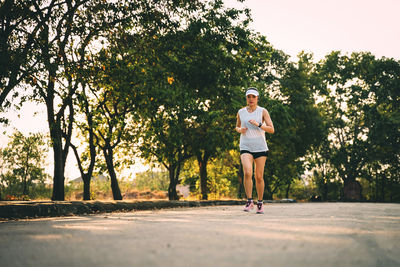 Full length of woman with arms raised on road