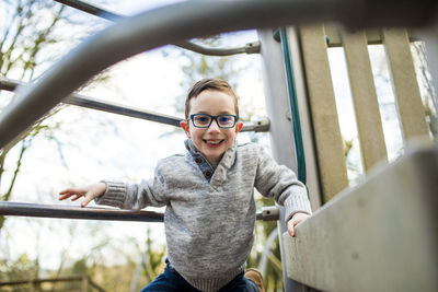 Portrait of young boy climbing on playground equipment.