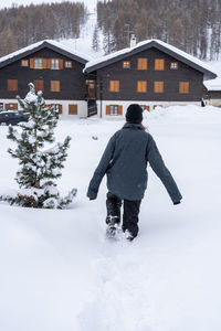 Rear view of teenage girl walking in fresh knee deep snow