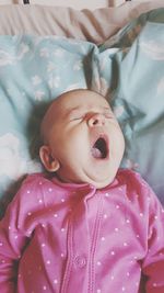High angle view of cute baby yawning on bed at home