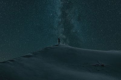 Person standing on snow covered landscape against star field