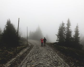 Rear view of man walking on footpath during winter