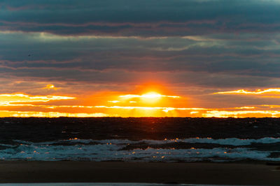 Scenic view of sea against dramatic sky during sunset