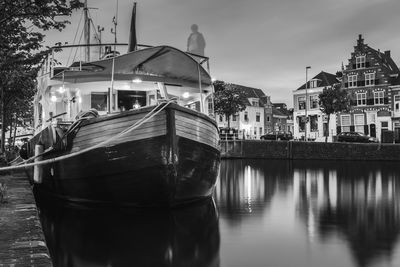 Boat moored at canal by buildings