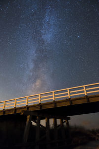 Low angle view of illuminated bridge against star field