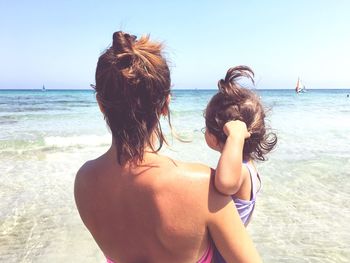 Rear view of woman on beach against sky