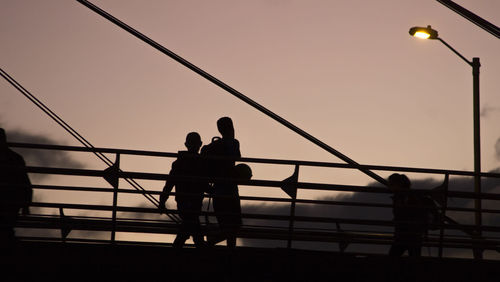 Silhouette people standing on bridge against clear sky at dusk