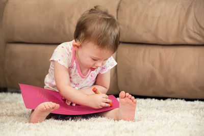 Cute girl sitting on rug at home