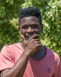 Portrait of young man standing against plants during sunny day