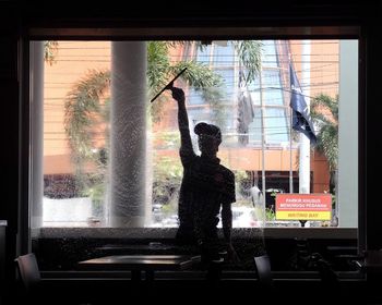 Silhouette of worker cleaning restaurant glass