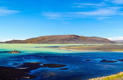 Scenic view of sea and mountains against blue sky