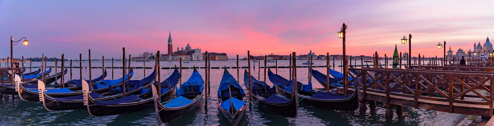 Boats moored in canal at sunset