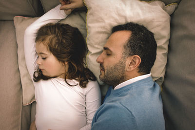 Directly above shot of father and daughter napping on couch at home