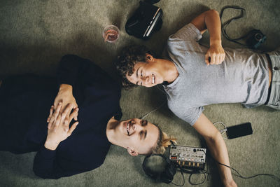 Male teenagers listening music while lying together on carpet at home