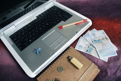 High angle view of laptop with money on table