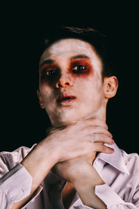 Close-up portrait of young man against black background