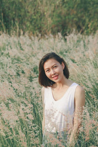 Portrait of smiling young woman standing on field