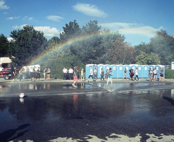 People on wet road against sky during rainy season