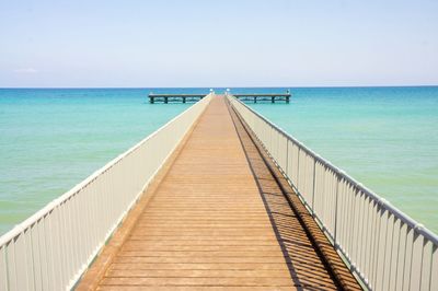 View of footbridge over sea against clear sky