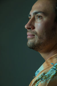 Close-up of man looking away against green background