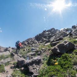 Rear view of man climbing on mountain against sky