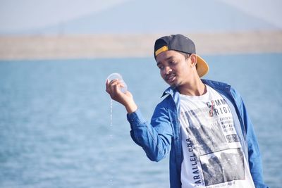 Smiling man standing in sea against sky