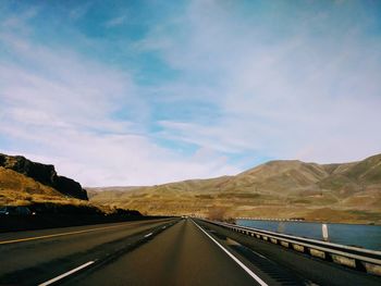 Road leading towards mountains against sky