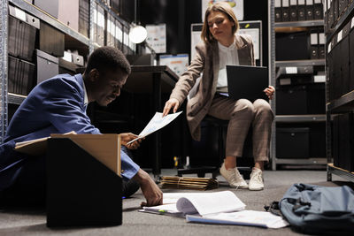 Side view of woman using digital tablet while sitting in office