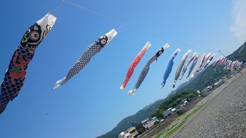 Low angle view of multi colored flags hanging against sky