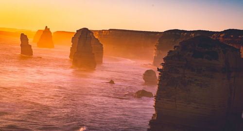 Rocks on sea against sky during sunset