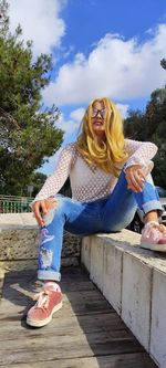 Full length of smiling woman sitting outdoors