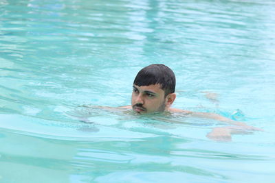 Headshot of a young man swimming in blue water