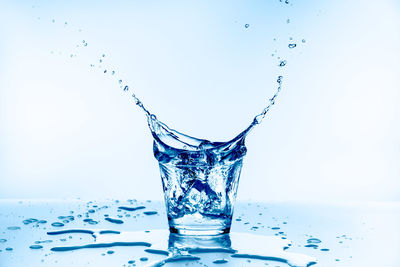 Close-up of water splashing on glass against white background