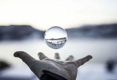 Close-up of hand holding crystal ball in snow