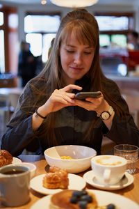 Smiling woman using mobile phone at cafe