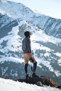 Rear view of man standing on snowcapped mountain