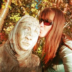 Portrait of young woman with sculpture in park