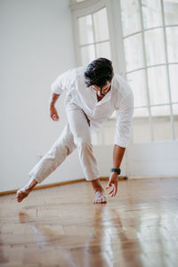 Full length of man with arms raised on hardwood floor