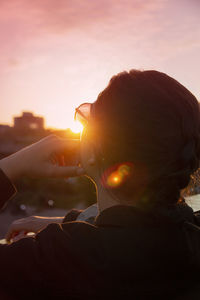 Rear view of teenage girl against sky during sunset