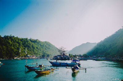 Boats moored in sea against clear sky