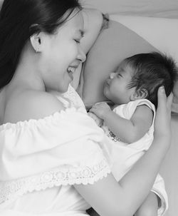 Midsection of mother and daughter baby on bed