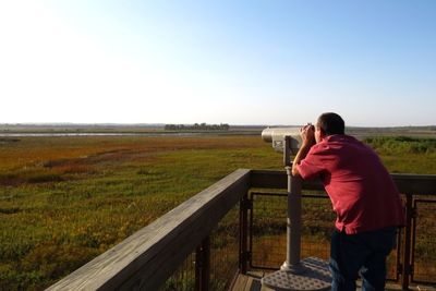 Man standing on grassy field against clear sky