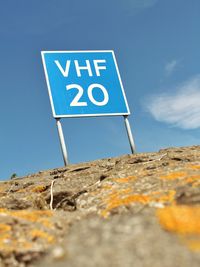 Low angle view of road sign against blue sky