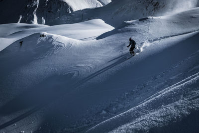 Man skiing on snowcapped mountain against sky