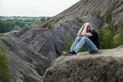 Rear view of man sitting on rock